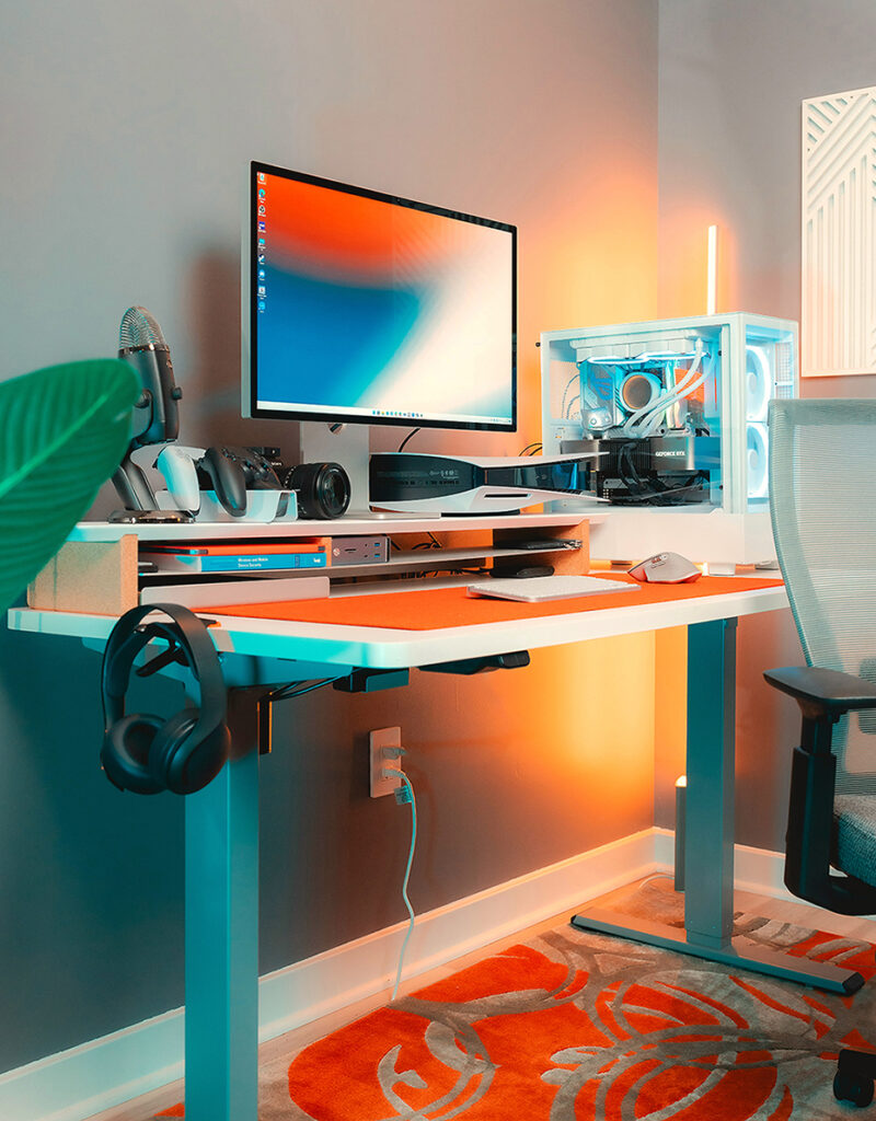 Bureau ultramoderne avec unité centrale transparente, accessoires de bureau design. Tonalités dominantes : bleu, blanc et orange